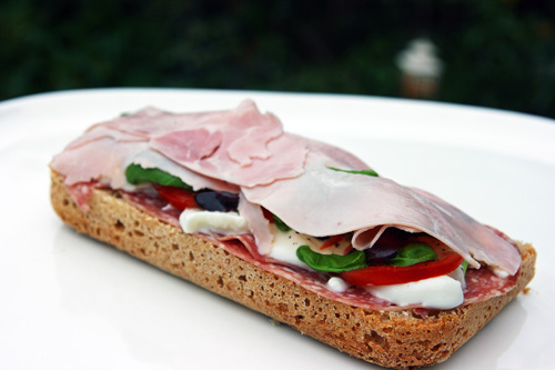 Sandwich med skinke, salami, mozarella, tomater, basilikum, oliven og olivenolie Sandwich med skinke, salami, mozarella, tomater, basilikum, oliven og olivenolie